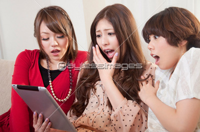素材 人物タブレットPCを見ながら笑う女性3人