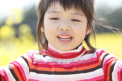 素材 人物菜の花畑に立つ小学生女子ポートレート