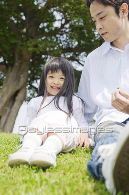 素材 人物公園の芝生に座る父娘