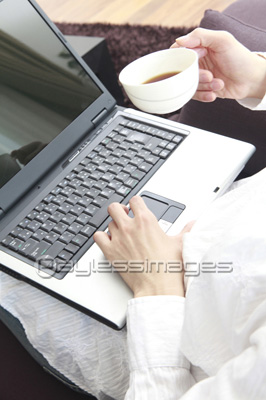 素材 人物コーヒーを飲みながらノートパソコンを使う男性の手元