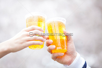 素材 人物桜の下で乾杯をする男性と女性の手元